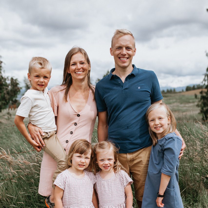 A photo of David, his wife, and four kids. They're standing, posed in a field.