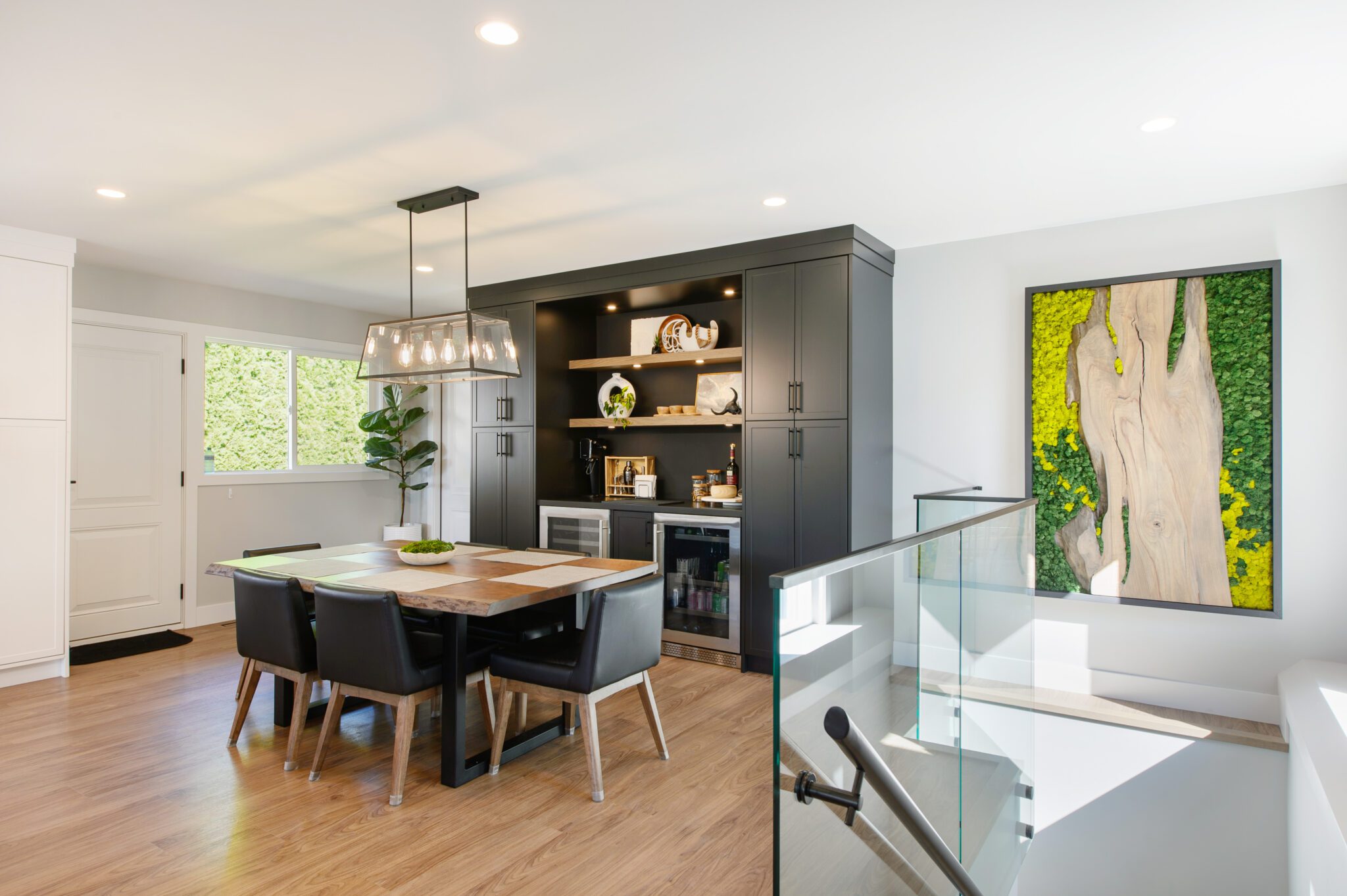 Glass stairway in lower right corner, leading up to dining room with black cabinet against white walls.