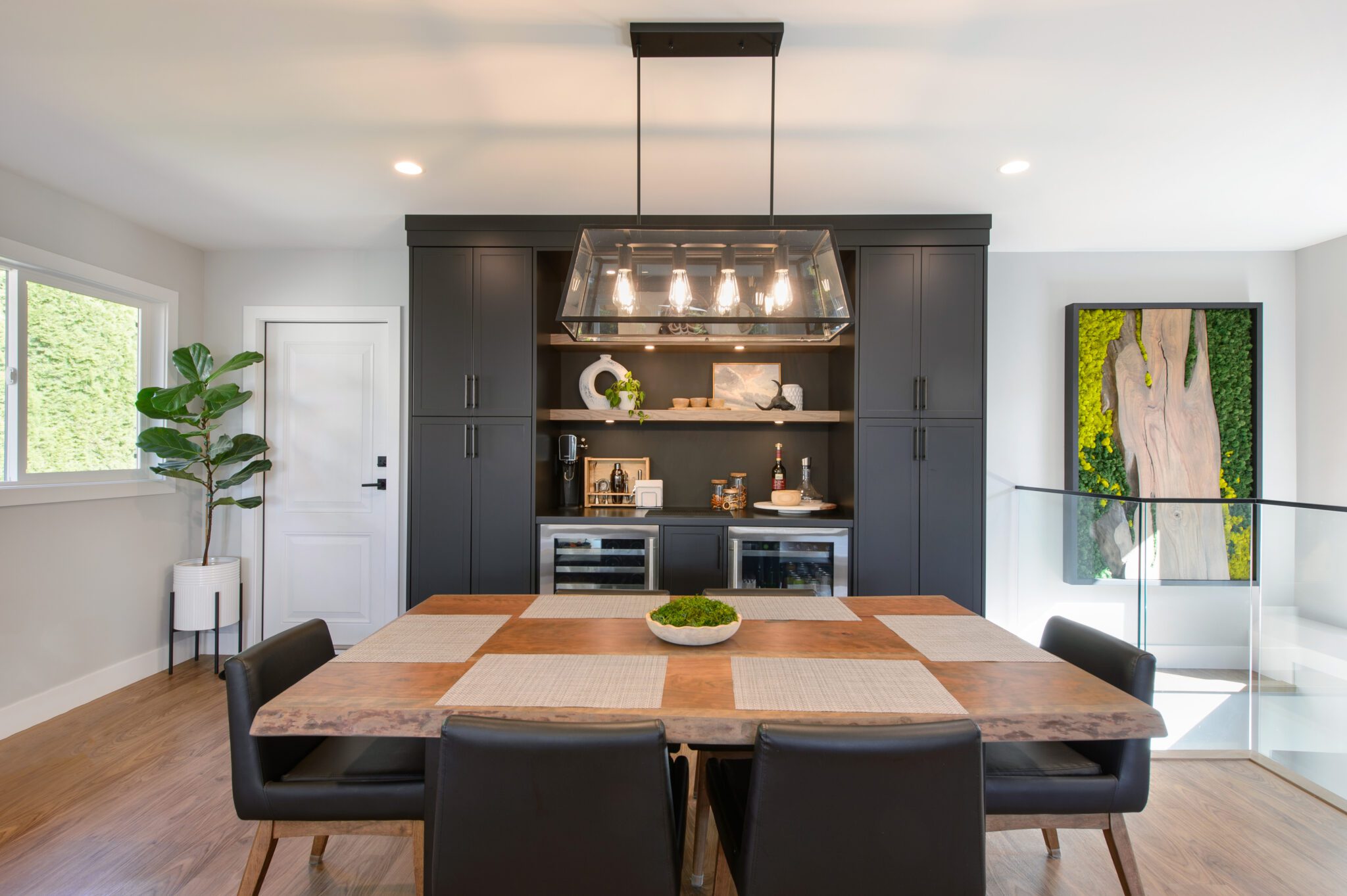 Warm, wooden dining table with black tables in foreground, and black cabinet in the background.