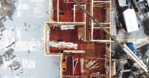 Aerial view of the wooden frame of a home. The landscape is covered in snow.